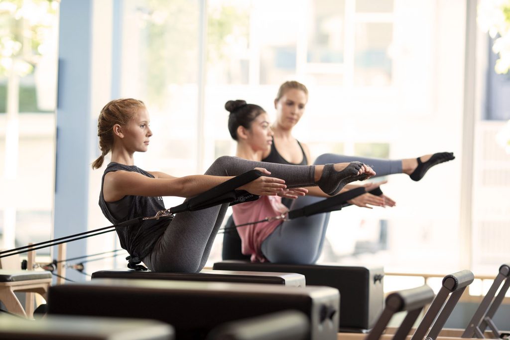 reformer pilates exercises - women doing Pilates